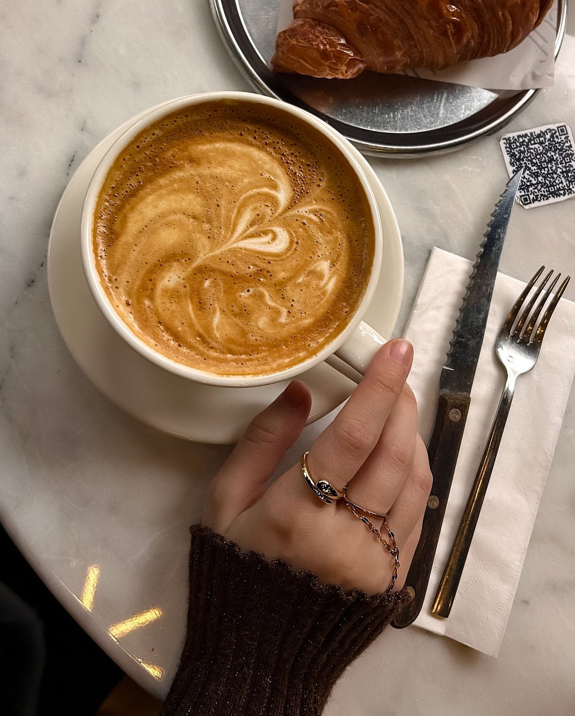 Bagues dorées portées autour d'un café et d'un croissant